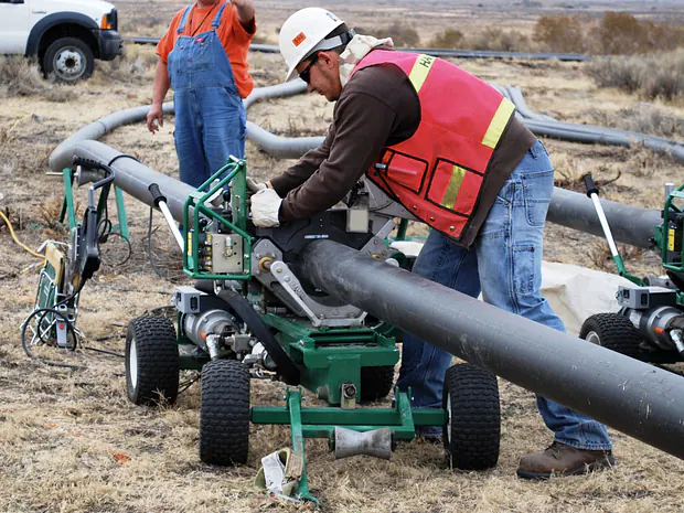 Dos operarios uniendo un caño de HDPE con una máquina de termofusión a tope en obra.